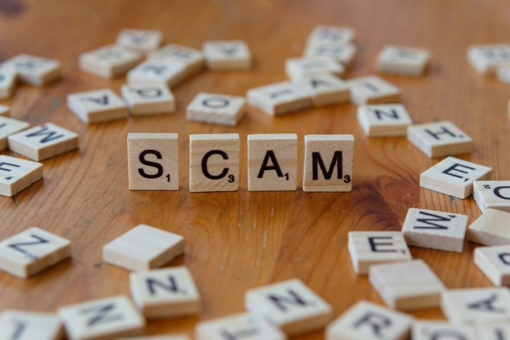 Scrabble tiles spelling the word SCAM on a wooden table, illustrating a guide to spotting phishing and scam messages